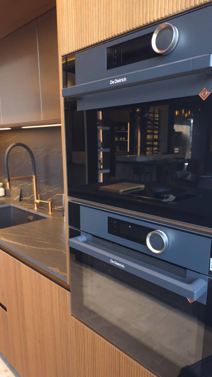 Détail de l’électroménager intégré dans une cuisine sur mesure en noyer naturel et cuivre